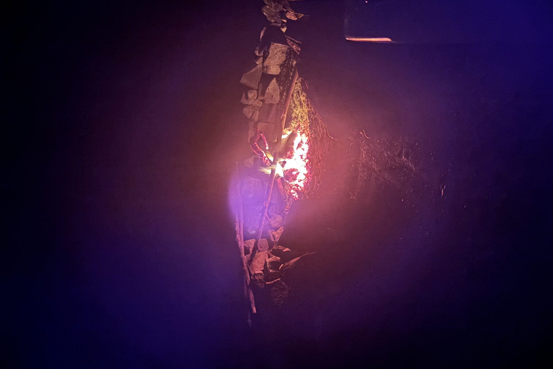 Embers glowing in a stone-ringed hearth at night
